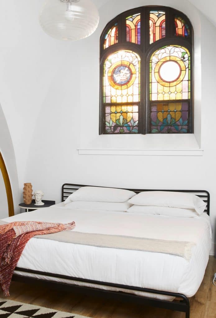guest bed in renovated church with stained glass window