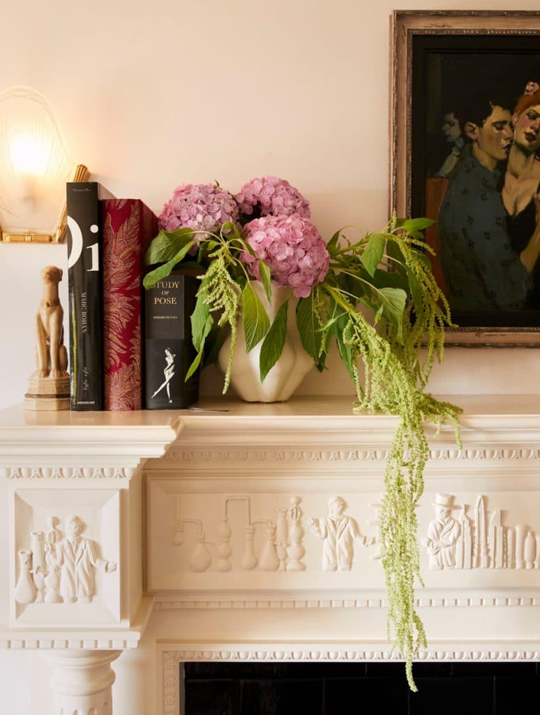 cream colored carved mantel with books and flowers on top