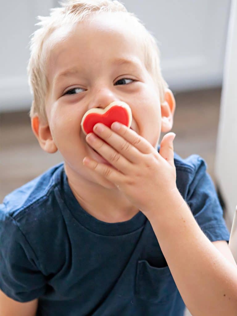 boy holding heart cookie over his mouth