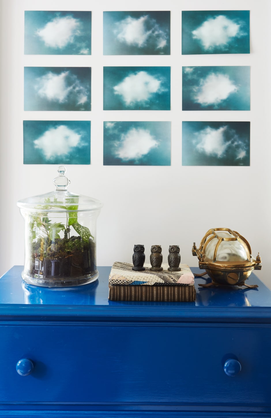 glossy blue dresser with grid of art above