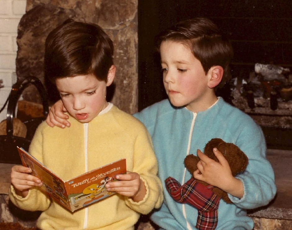 Drew and Jonathan read by the fireplace in their PJs