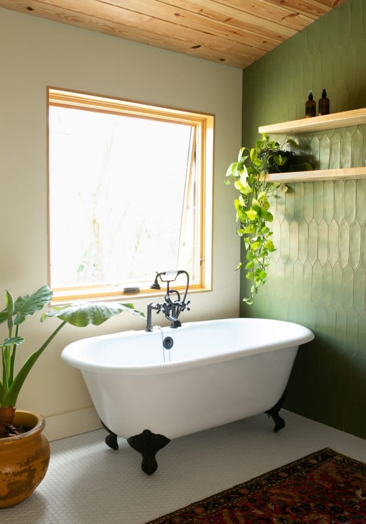 master bathroom with green accent wall and white claw foot bathroom