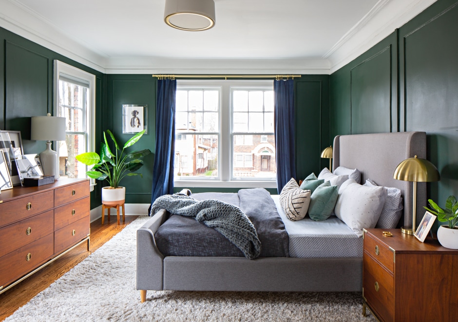 cozy dark green, blue, and gray bedroom with plants and wood furniture
