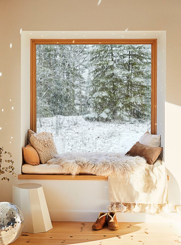 cozy window seat with neutral colored pillows and blankets and disco ball