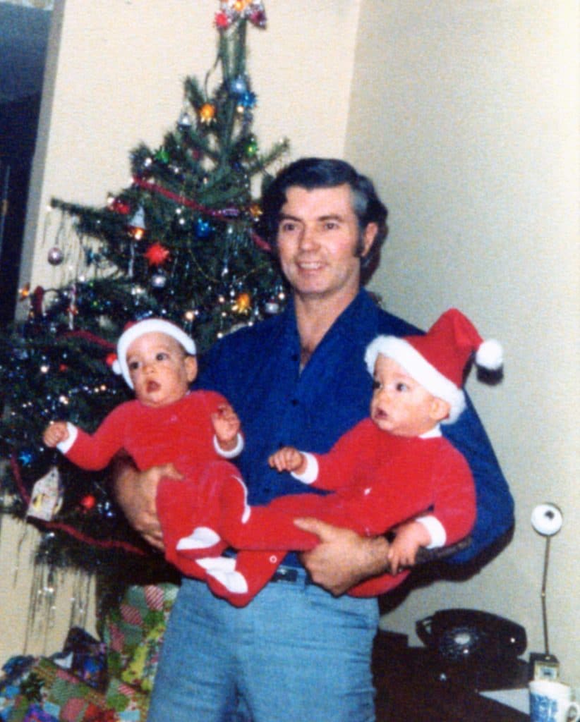 dad holding twins dresses as santas
