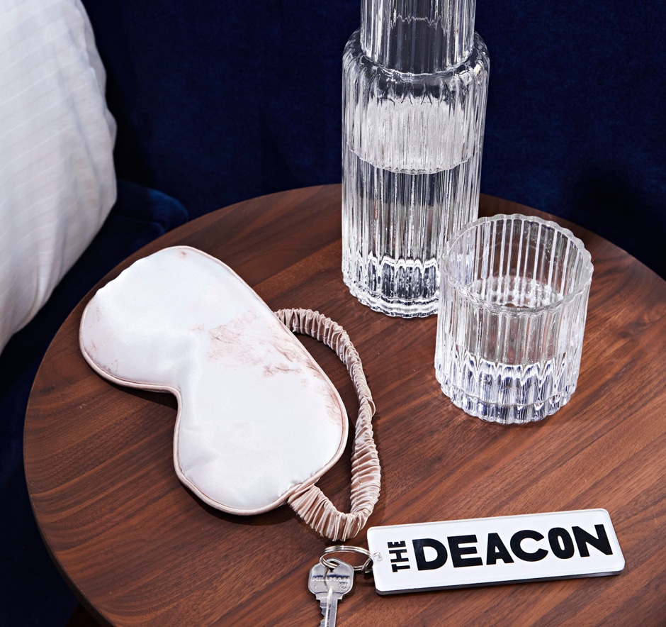 sleep mask and deacon room key on bedside table