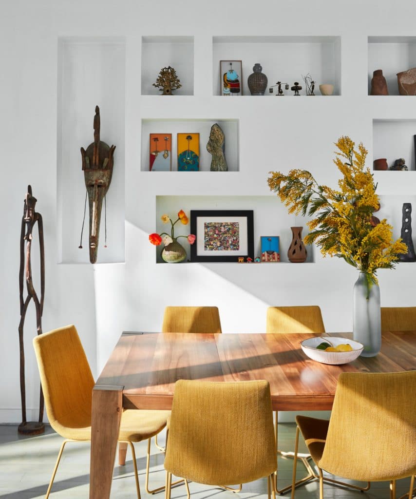 modern wooden dining room table with yellow. chairs and art on the walls