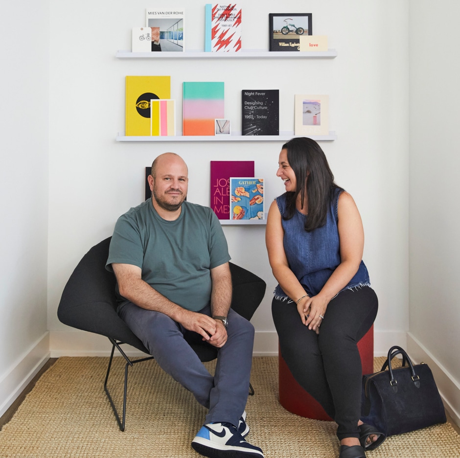 Everett and Valerie sitting in chairs with graphics and books on shelf behind