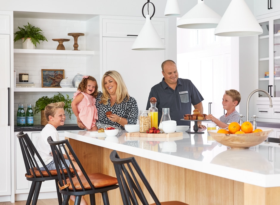 family smiling and eating breakfast in white kitchen