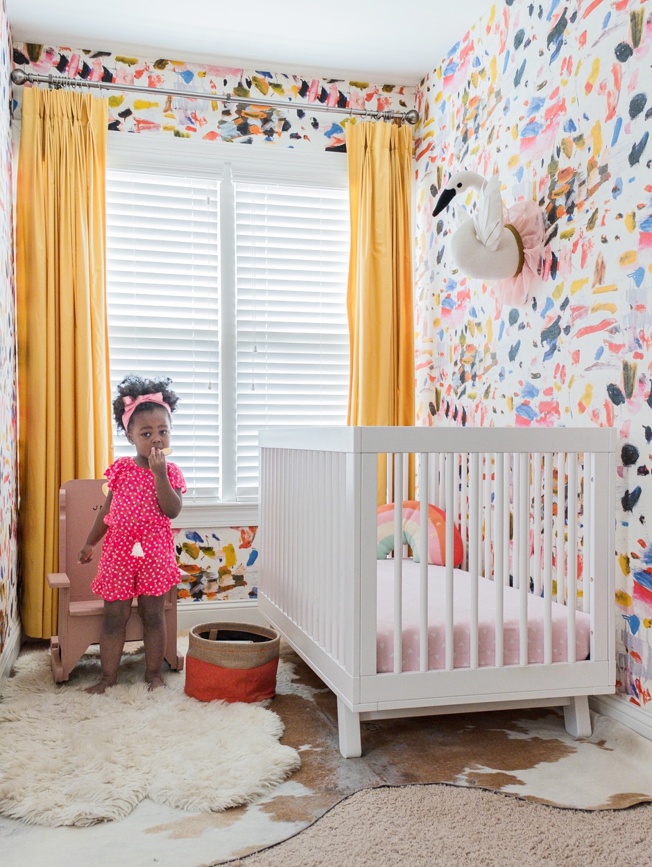 girl standing in colorful abstract wall nursery