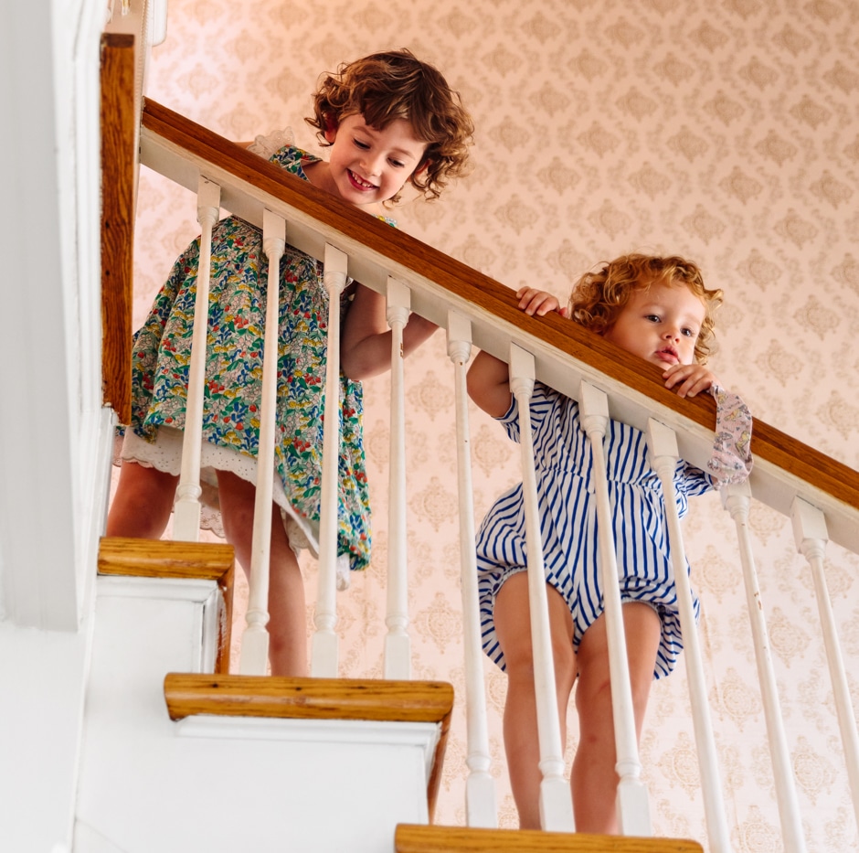 two daughters standing on wooden stairs leaning against railings