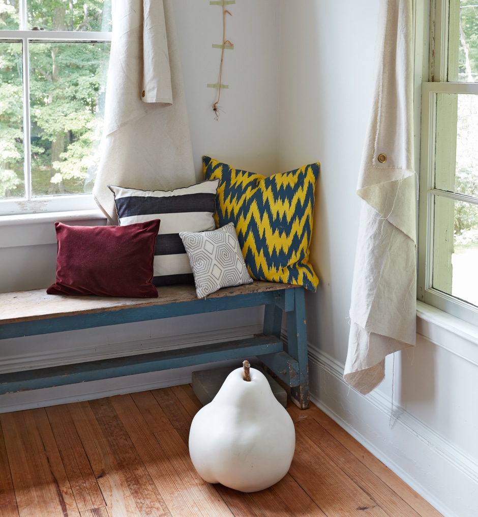 corner of guest bedroom with rustic bench and pear sculpture