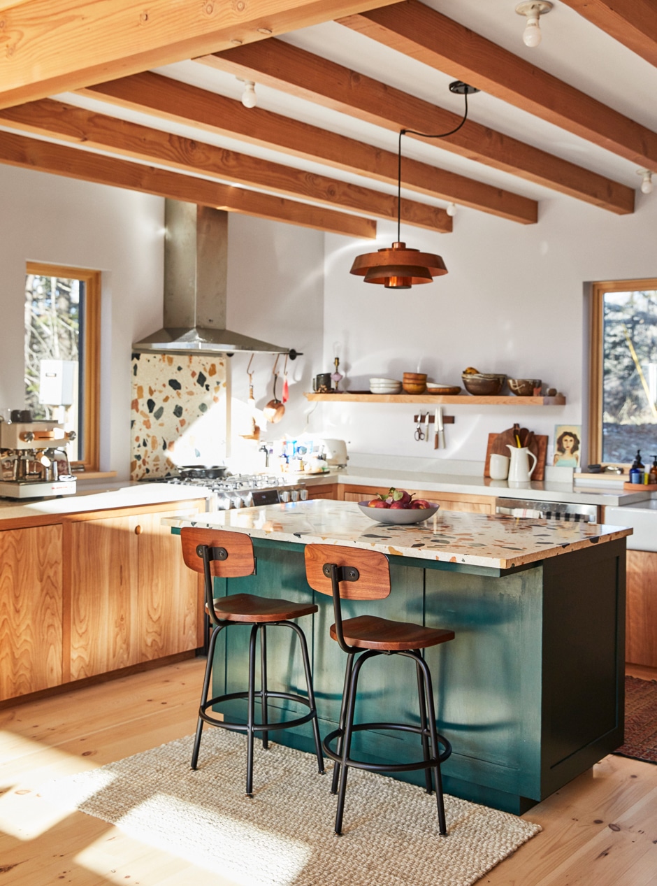 beautiful midcentury modern kitchen with natural light, wooden floors and cabinets, terrazzo counter tops and dark green accents