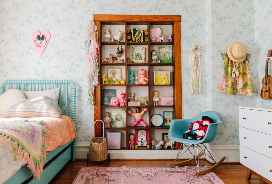 wooden shelving unit in pastel wallpapered daughter's bedroom