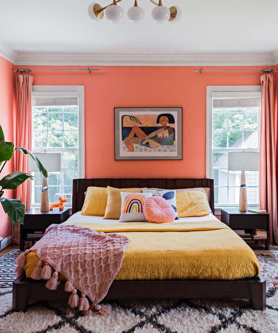 coral and yellow bedroom with African art above bed