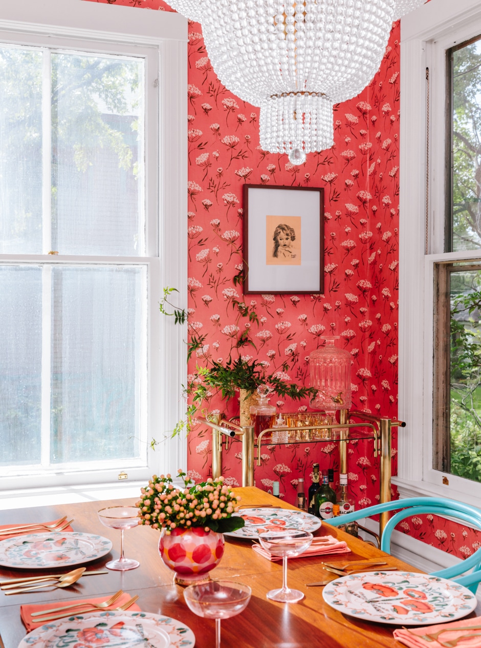 coral wallpapered dining room with teal chairs