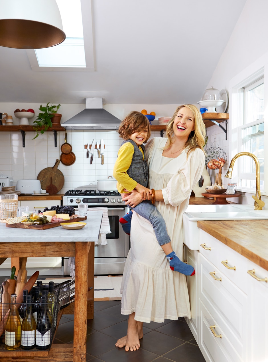 Sarah holding son in modern white and wooden kitchen