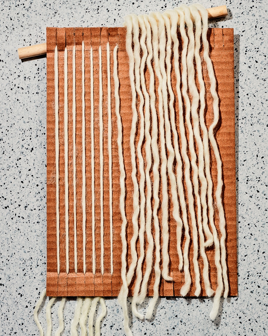 threading yarn through cardboard loom