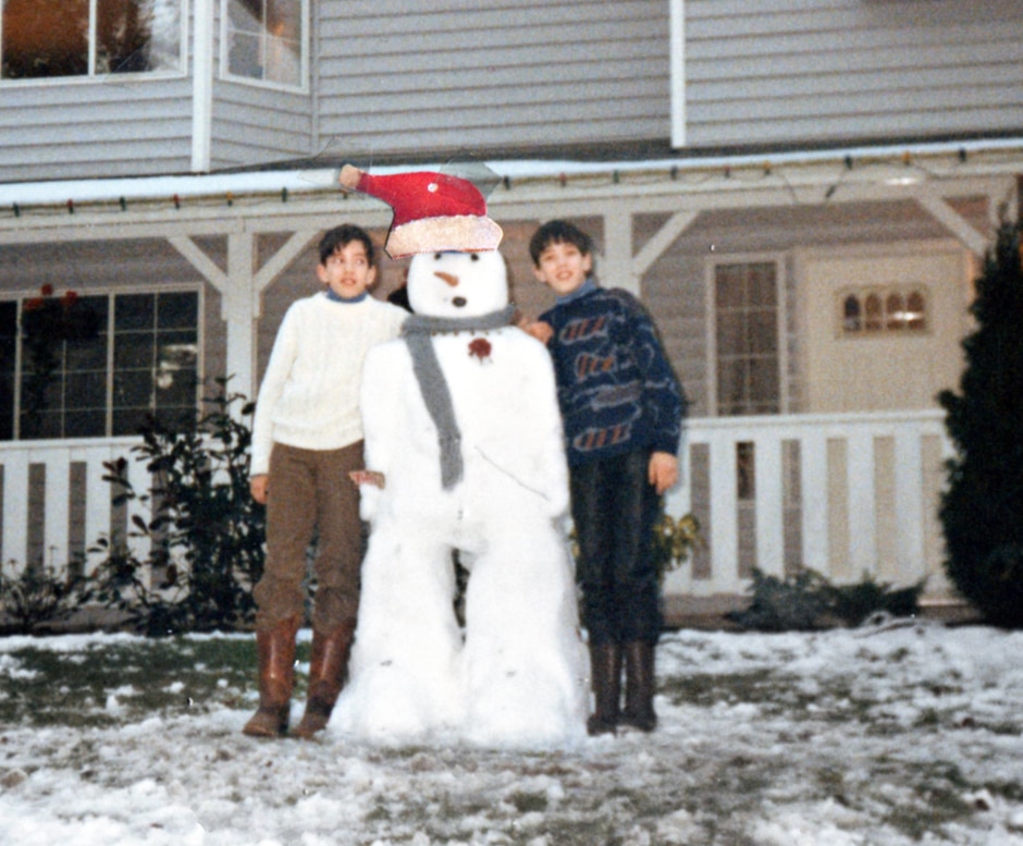 twins posing with snowman wearing santa hat