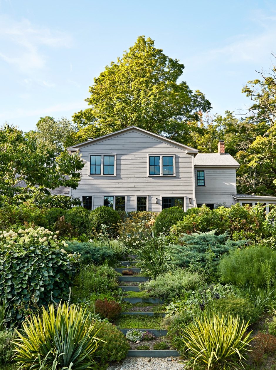 white home exterior with lush greenery gardens surrounding