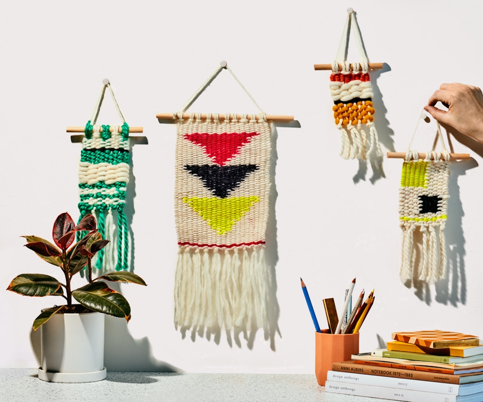 woven wall hangings against beige surface with plant and books