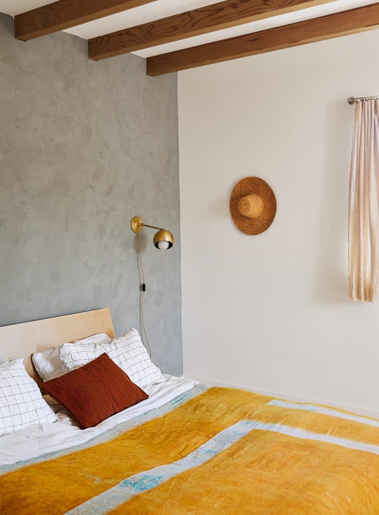 bedroom with gray textured wall and bed with mustard yellow blanket