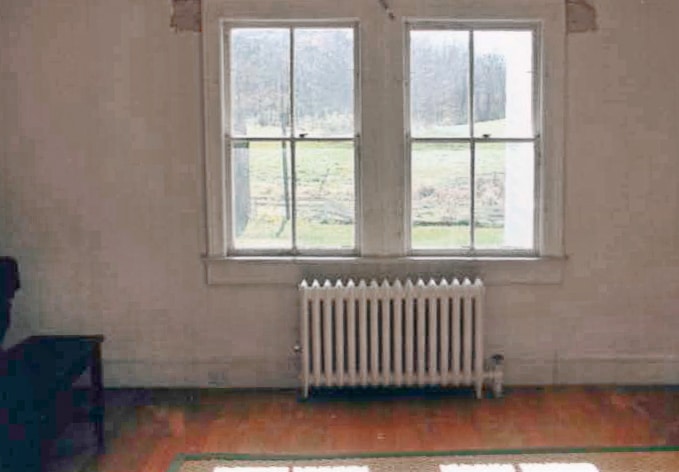 room with windows and old heater before renovation