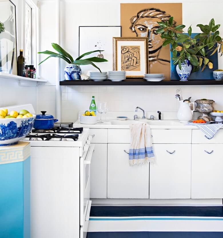 Blue and white kitchen with a floating shelf holding dishes and decor