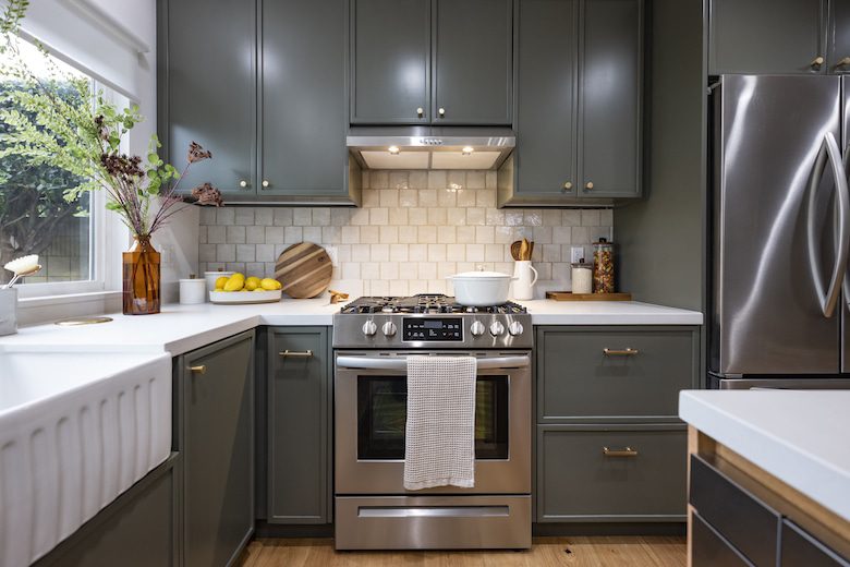 Kitchen with green cabinets and stainless steel stove