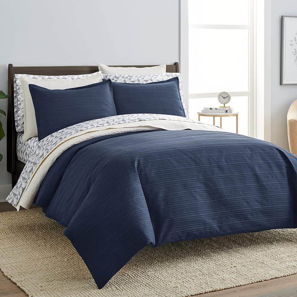 Bed with navy blue duvet cover, geometric-patterned sheets, and matching pillows