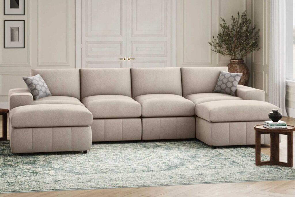 Light beige sectional sofa with decorative pillows, coffee table, and a potted plant in a living room