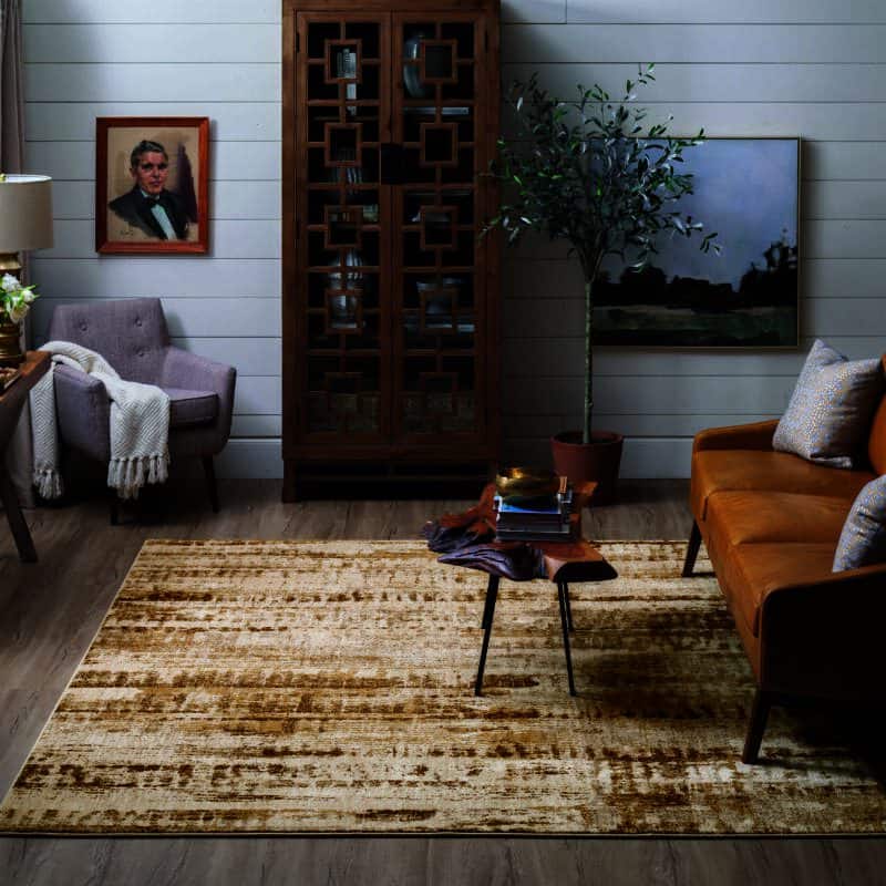 Cozy living room with a mustard sofa, wooden cabinet, abstract artwork, and a textured area rug