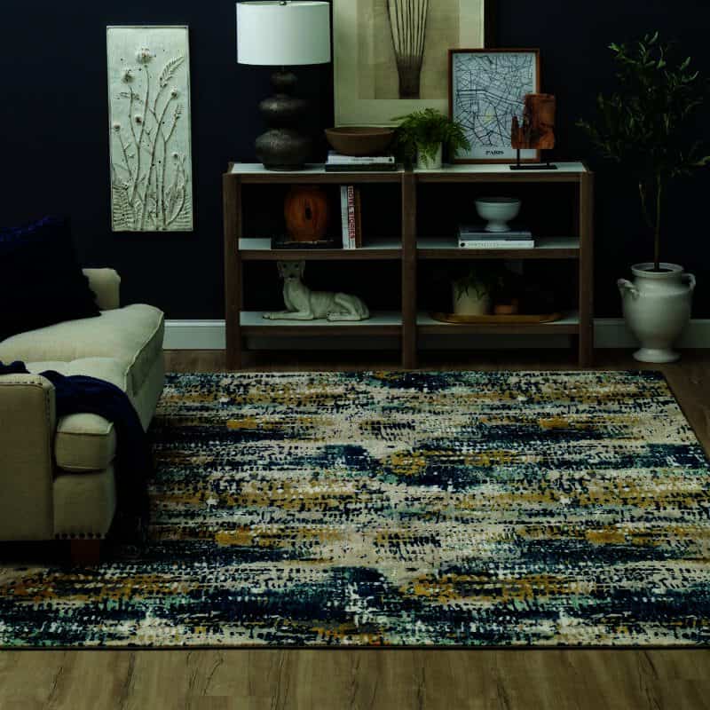 Multicolor abstract rug in a cozy, dark-toned living room with neutral furniture and decorative shelving