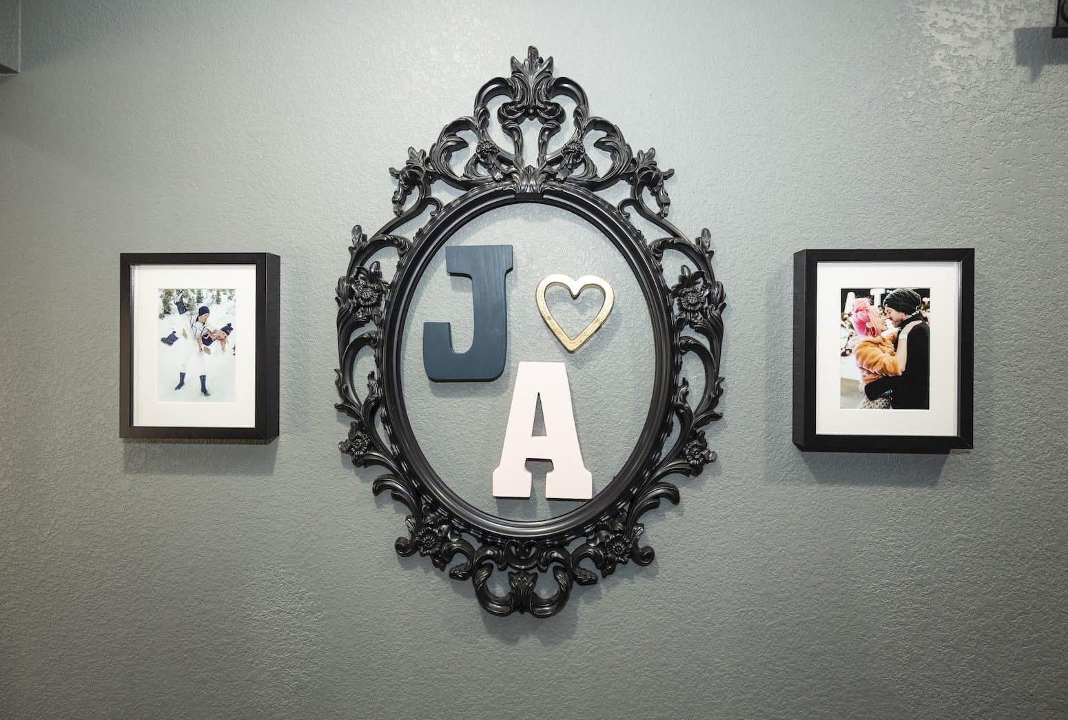Decorative wall display with an ornate black frame, initials, and framed photos