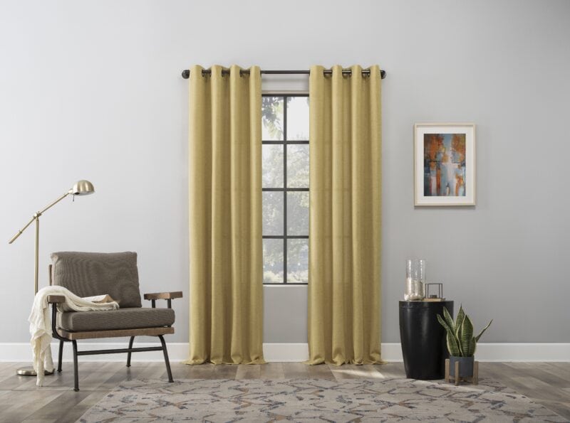 Modern living room with mustard yellow curtains, gray armchair, brass floor lamp, and abstract wall art