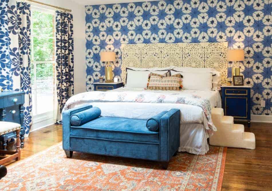 A decorated bedroom with a large bed, blue nightstands, and a patterned area rug