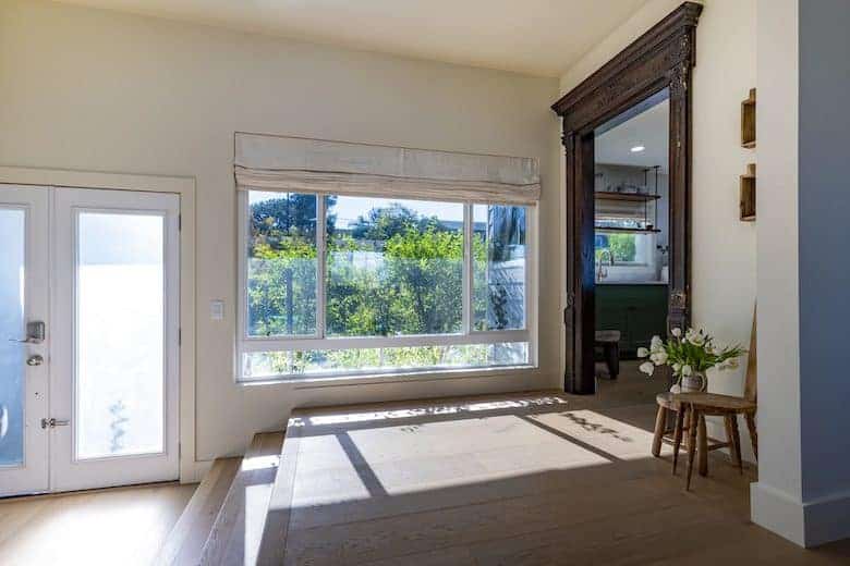 Bright entryway with large windows, natural light, a vintage wood frame doorway, and minimalist decor