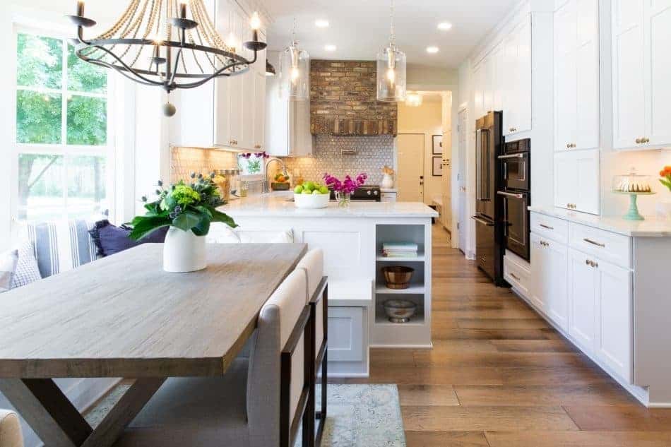 Farmhouse kitchen with white cabinets, a large island, and a brick accent wall