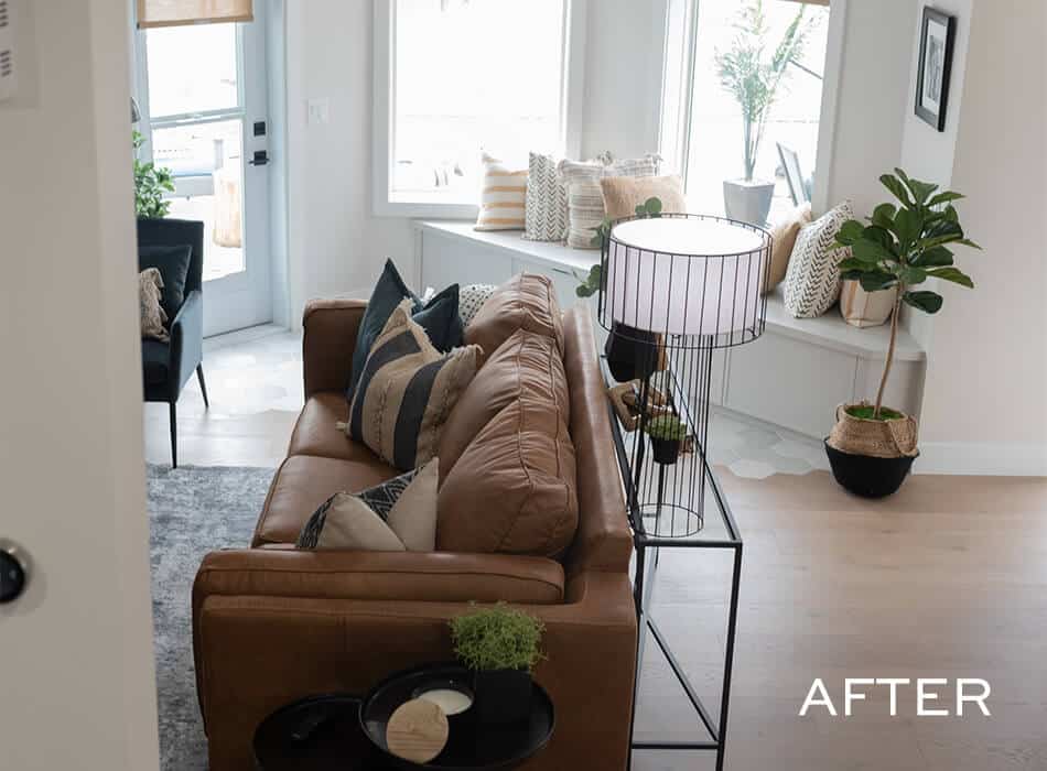 Living room with brown leather sofa decorative pillows black side table and indoor plants