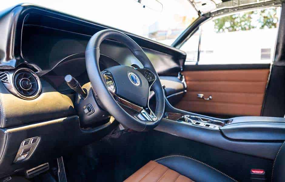 Luxury car interior with black leather steering wheel tan upholstery and modern dashboard
