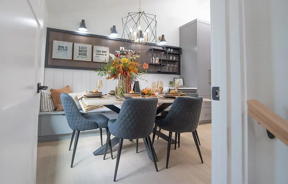 Dining room with dark wood accents, quilted chairs, and a modern chandelier