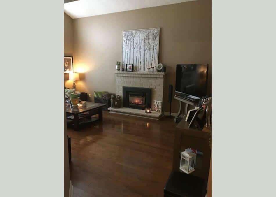 Living room with a neutral palette, a white brick fireplace, hardwood floors, and warm ambient lighting