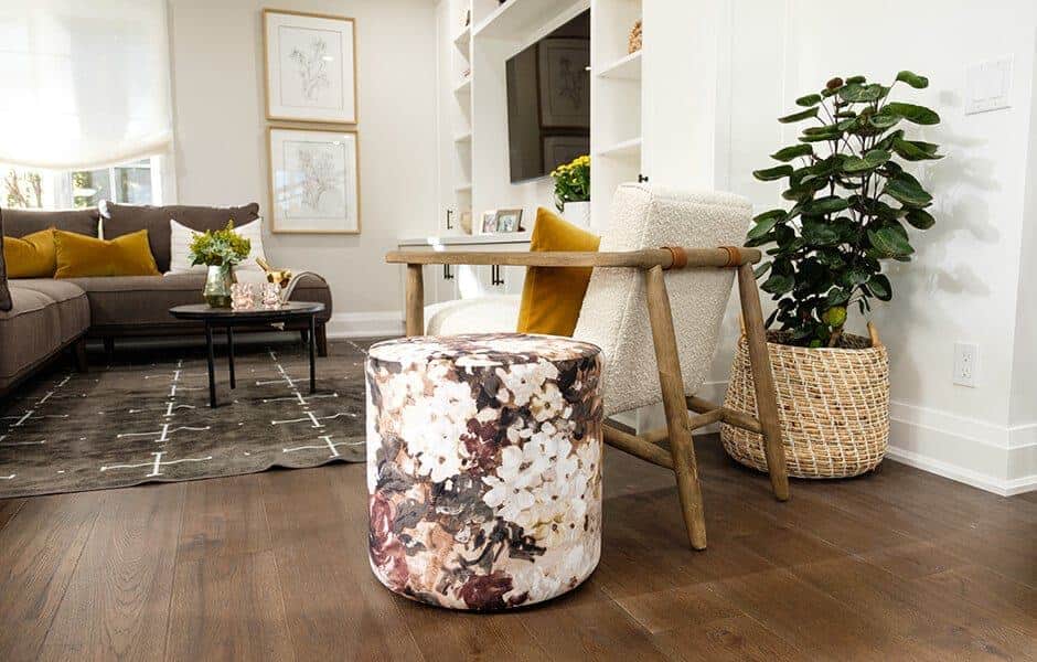 Cozy living space with floral ottoman, wooden chair, and vibrant decor accents