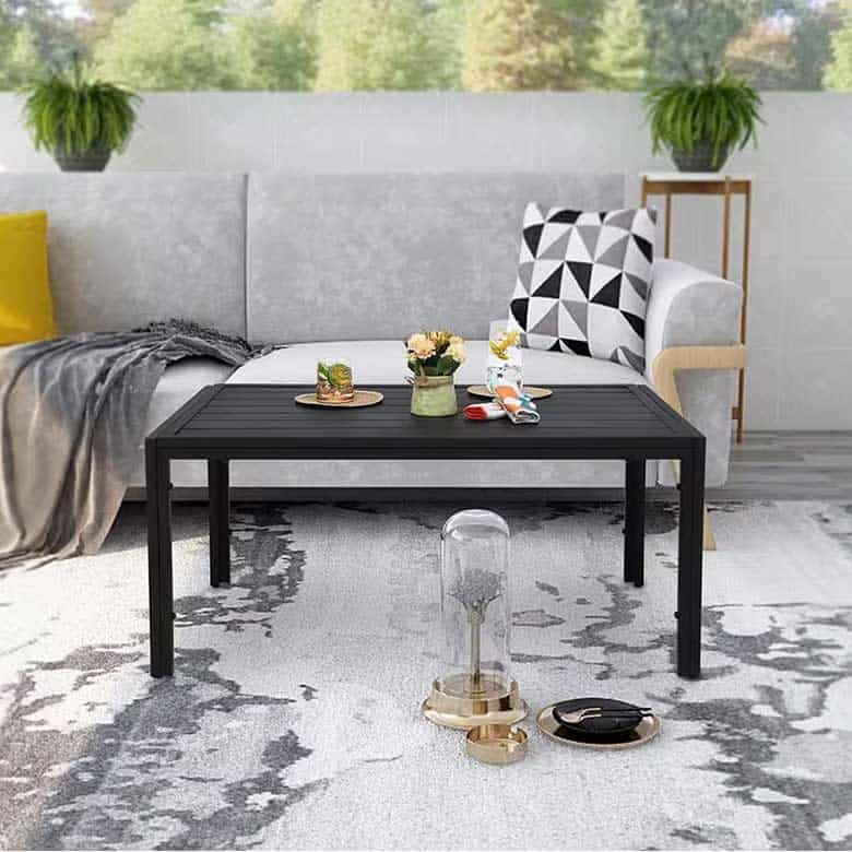 Modern living room with light gray sofa, black coffee table, geometric pillow, and abstract area rug