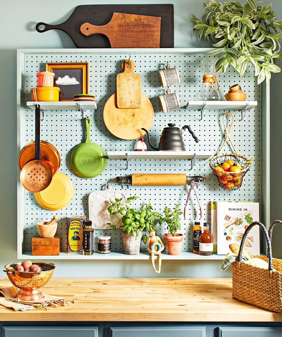 pegboard wall storage in kitchen with pots, pans, cutting boards, and assorted tools