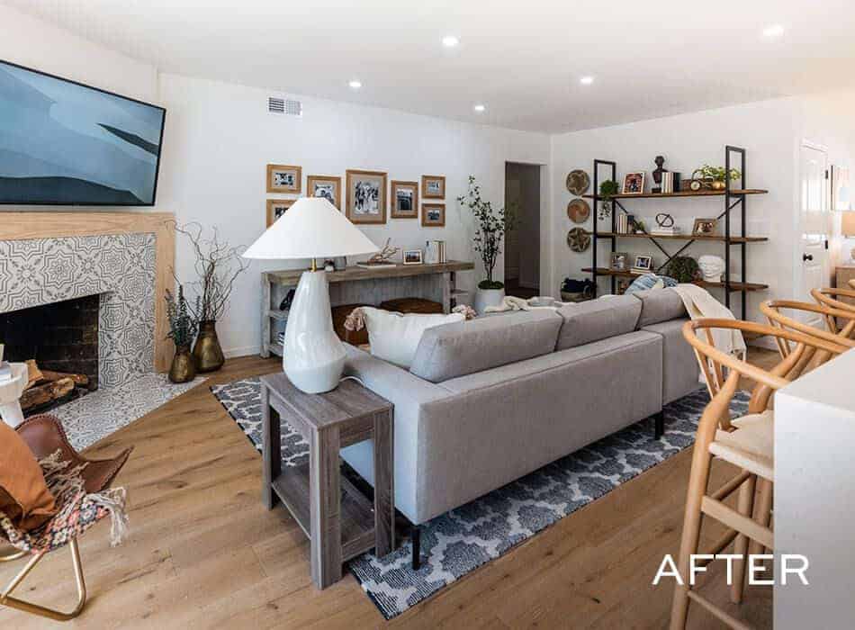 Living room with a gray sectional sofa, a tiled fireplace, wooden shelving, and a wall-mounted TV