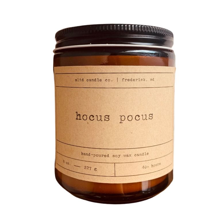 Amber glass jar candle with kraft paper label reading hocus pocus hand poured soy wax