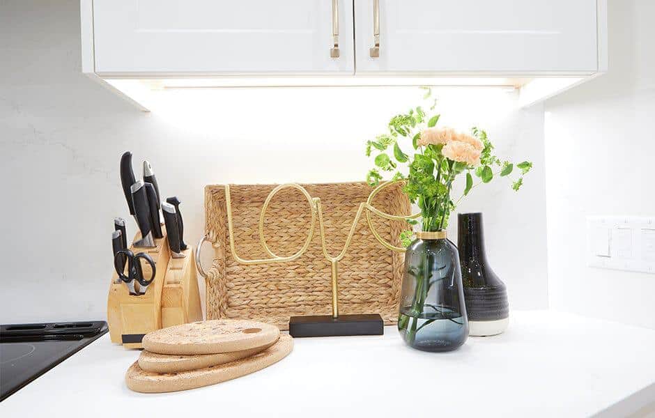Kitchen countertop with a knife block, woven basket, decorative vases, and a gold "LOVE" sign