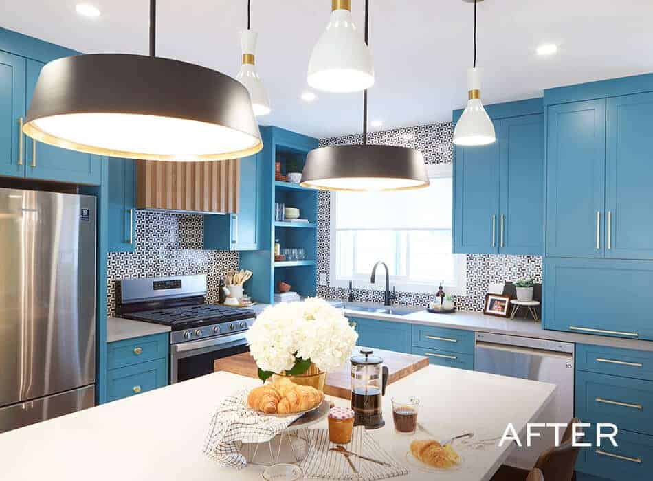 Bright kitchen with blue cabinets, gold hardware, black pendant lights, and a white island set for breakfast