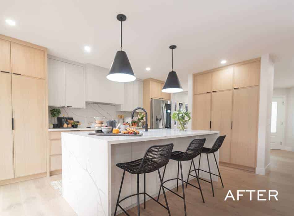 Bright modern kitchen with light wood cabinets, a marble island, and black pendant lights